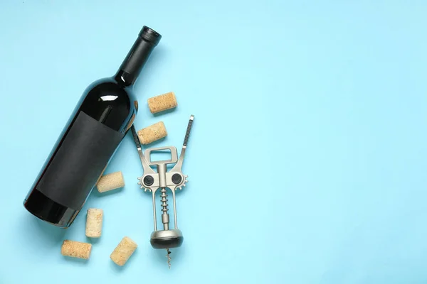 Bottle of wine, corks and opener on blue background