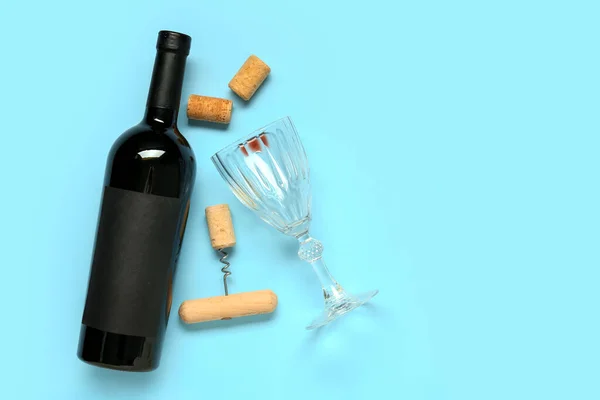 Bottle of wine, corks, glass and opener on blue background