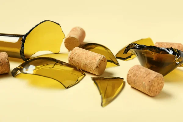 Broken wine bottle and corks on beige background