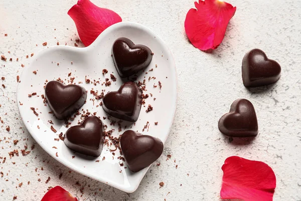 Teller Mit Leckeren Herzförmigen Bonbons Und Rosenblättern Auf Hellem Hintergrund — Stockfoto