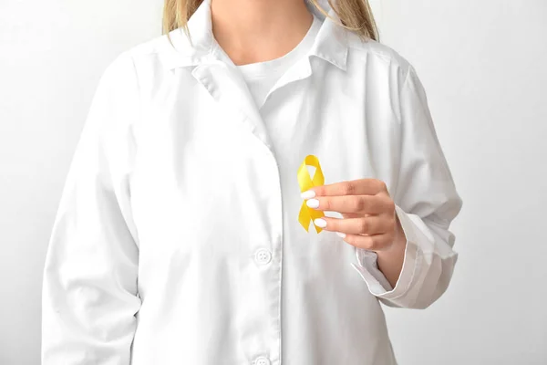 女医生手握金黄色的意识带 背景浅 国际儿童癌症日 — 图库照片