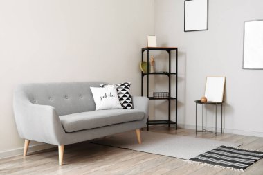 Dekorlu raf ünitesi, kanepe ve aydınlık odada boş fotoğraf çerçeveleri