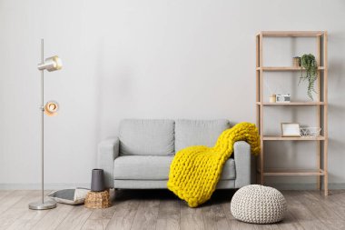 Yer lambası, kanepe, raf ünitesi ve odanın ışık duvarının yanında puf.