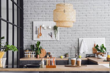 Modern mobilyaları ve gri tuğlalı duvarları olan şık bir mutfak.