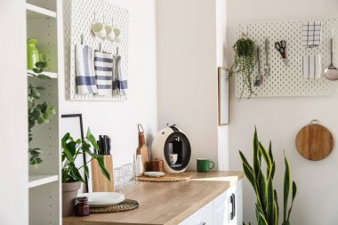 Mutfak eşyaları ve modern kahve makinesi, ışık duvarının yanındaki ahşap masada.