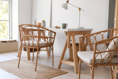 Odanın içinde tahta masa ve hasır sandalyeler.