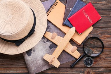 Hasır şapka, uçak, pasaport, büyüteç ve ahşap zemin üzerinde klasik harita.