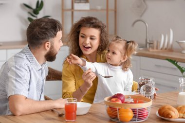 Genç ve mutlu bir aile mutfakta kahvaltı yapıyor.