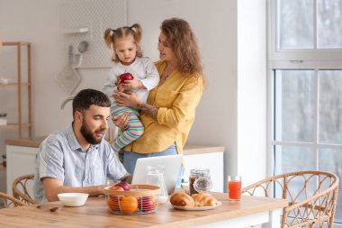 Genç ve mutlu bir aile mutfakta kahvaltı yapıyor.