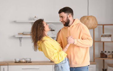 Mutlu çift evde mutfakta dans ediyor.