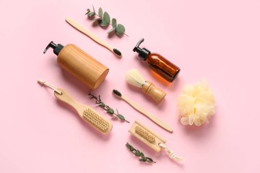 Banyo malzemeleri ve pembe arka planda okaliptüs dalları olan kompozisyon