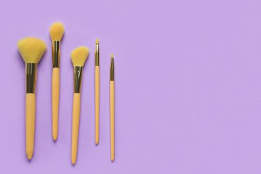 Mor arkaplanda makyaj fırçaları