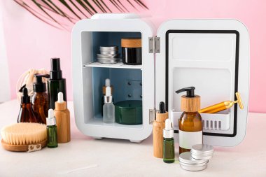 Işık masasında kozmetik ürünleri olan küçük bir buzdolabı.
