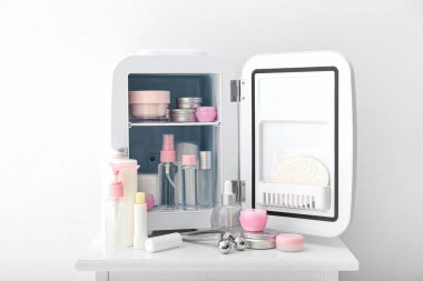 Masada kozmetik ürünleri olan küçük bir buzdolabı.