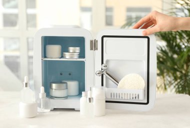 Masada kozmetik buzdolabı olan bir kadın eli.