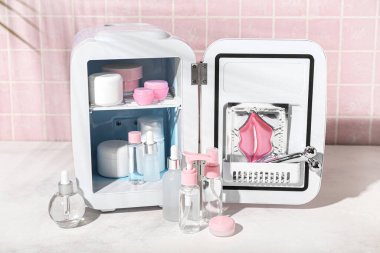 Masada kozmetik ürünleri olan küçük bir buzdolabı.