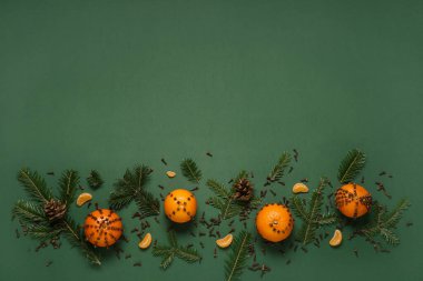 Yeşil arka planda karanfilli mandalinalardan yapılmış el yapımı Noel süsü.