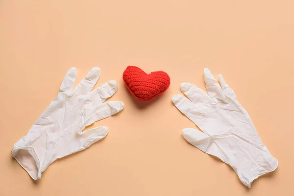 Medical gloves and red heart on color background. Donation concept