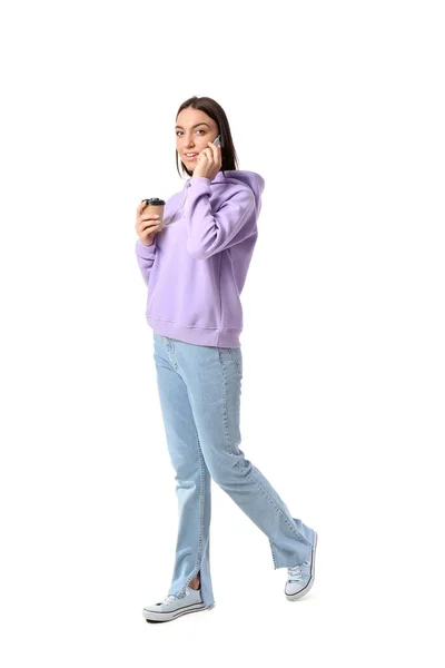 若いです女性でLilacパーカーとともにコーヒーカップの携帯電話によってホワイトバック — ストック写真