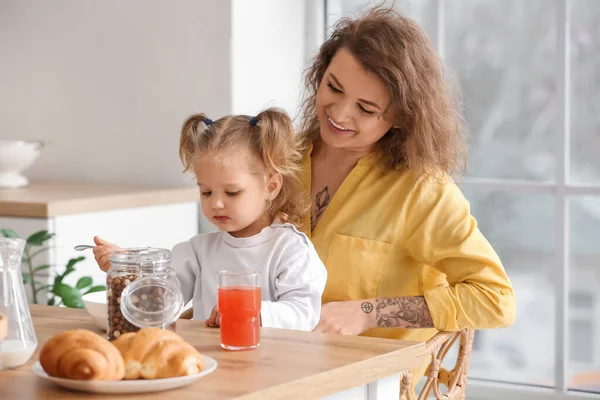 快乐的年轻妈妈带着她的小女儿在家里厨房里吃早餐 — 图库照片