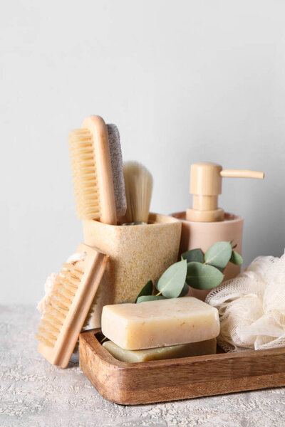 Different bath supplies with soap bars on light background