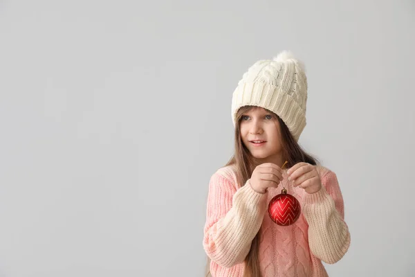 Χαριτωμένο Κοριτσάκι Χειμωνιάτικα Ρούχα Και Χριστουγεννιάτικη Μπάλα Γκρι Φόντο — Φωτογραφία Αρχείου