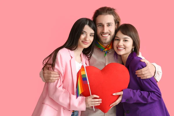 男人和两个漂亮的女人带着彩虹旗和心形枕头的彩色背景 一夫多妻制和男女同性恋 双性恋和变性者的概念 — 图库照片