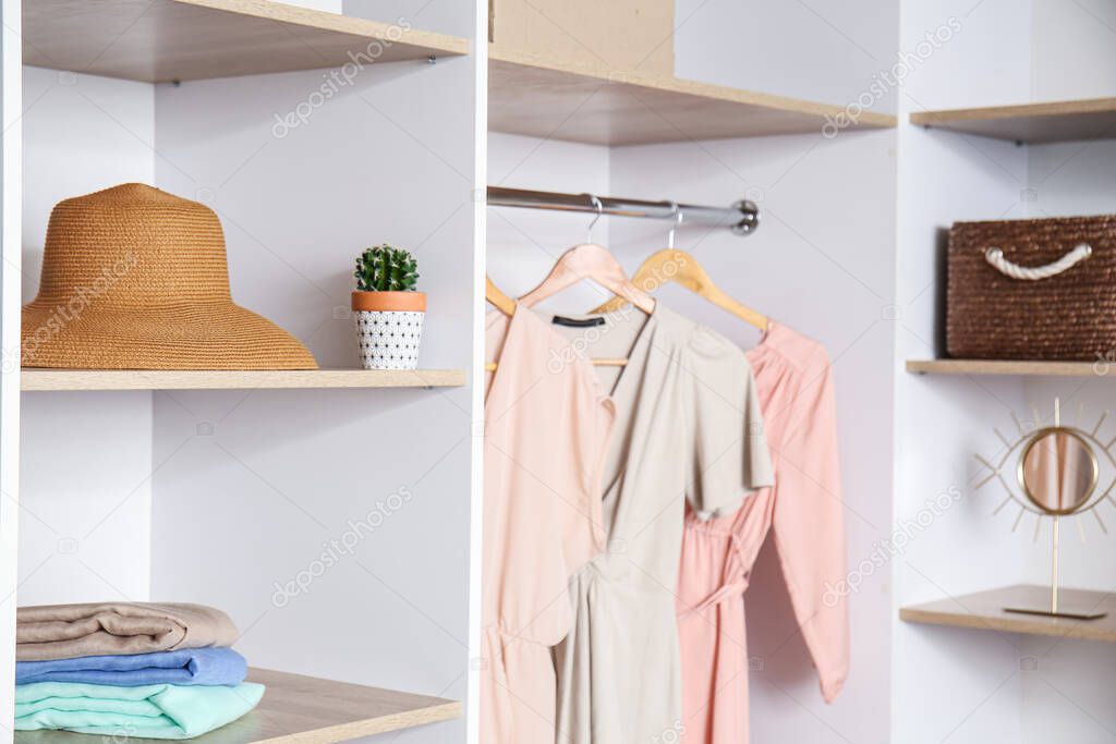 Stylish hat and female clothes in wardrobe, closeup