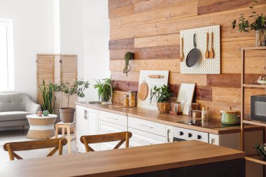 Modern mutfağın içinde beyaz tezgahlar, tahta tahtalar ve ahşap duvarlar var.