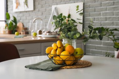 Şık mutfaktaki masada taze meyve dolu sepet.