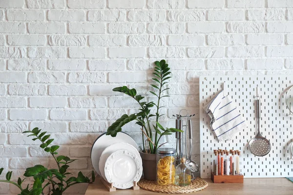 白いレンガの壁の近くのカウンターのキッチンウェアと観葉植物 — ストック写真