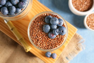 Bir bardak tatlı yoğurt, keten tohumu ve yabanmersini renkli arka plan, yakın plan.