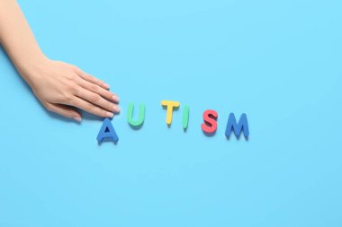 Renk arkaplanında AUTISM sözcüğüne sahip kadın el