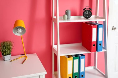 Renk duvarının yanında dizinleri olan raf ünitesi