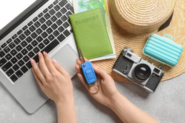 Anahtarlığı olan bir kadın, arka planda dizüstü bilgisayar kullanıyor. Araba kiralama konsepti