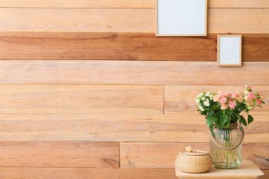 Güzel güller ve sepetle ahşap duvarın yanındaki masada.