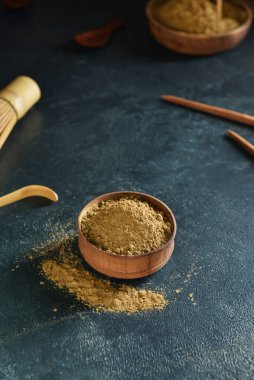 Siyah arka planda hojicha pudrası olan kase