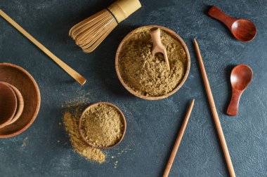 Siyah arka planda hojicha tozu, chashaku ve chasen içeren kaseler.