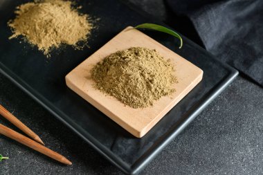 Siyah arkaplanda hojicha pudrası olan tahta, kapat