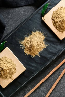 Siyah arkaplanda hojicha pudrası olan tahta, kapat