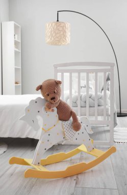 Oyuncak ayı yatak odasının yanındaki sallanan atın üstünde oturuyor.