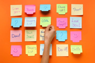 Kadın eli ve kırmızı arkaplanda farklı yapışkan notlar