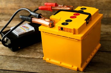 Ahşap arka planda modern araba aküsü ve test cihazı