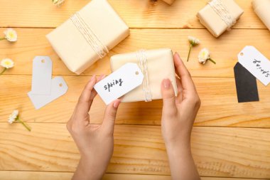 Sözcüklerle etiketlenmiş bir kadın ve tahta arka planda hediye kutusu.