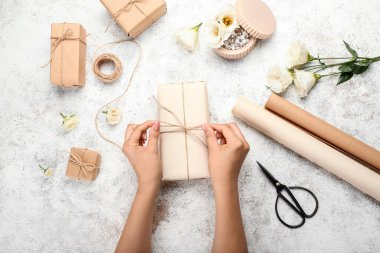 Kadın Grunge arka planında hediye kutusu paketliyor