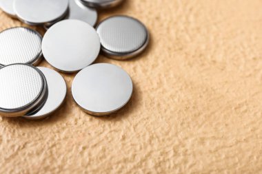 Bej arkaplanda lityum düğmeli hücre pilleri, yakın plan