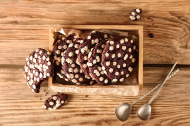 Tahta arka planda beyaz çikolata parçalı bir kutu lezzetli kurabiye.