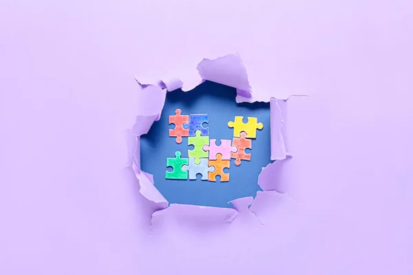 破れた紙の穴から見えるカラフルなパズルピース 自閉症障害の概念 — ストック写真