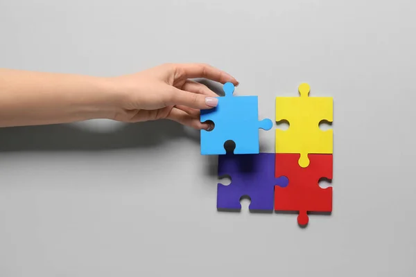 Vrouwelijke Hand Met Kleurrijke Puzzelstukjes Lichte Achtergrond Begrip Autistische Stoornis — Stockfoto