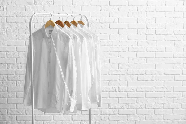 Rack Met Schone Shirts Plastic Zakken Witte Bakstenen Achtergrond — Stockfoto